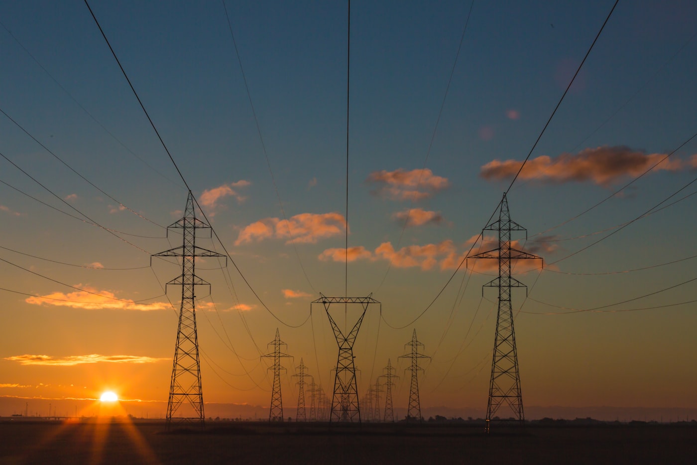 Transmission lines crossing open country at sunset